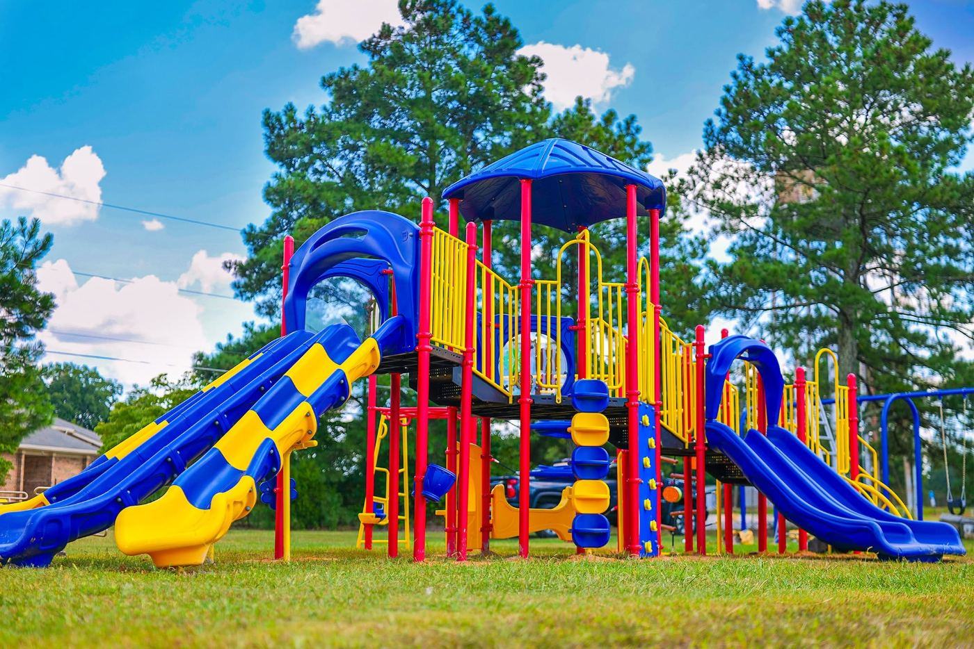 A commercial play structure with double slides, climbers and a shaded tower
